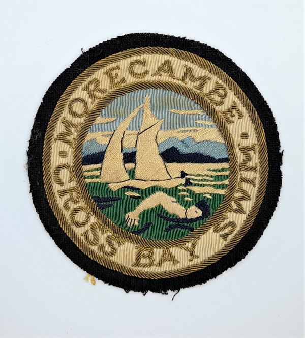 Embroidered fabric patch with images of a swimmer and sailing boat.